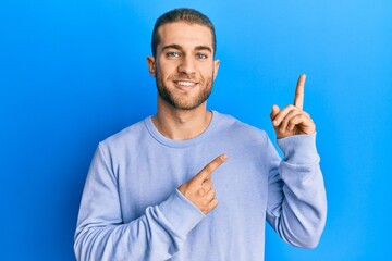 Fototapeta premium Young caucasian man wearing casual clothes smiling and looking at the camera pointing with two hands and fingers to the side.