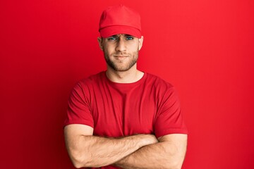 Young caucasian man wearing delivery uniform and cap skeptic and nervous, disapproving expression on face with crossed arms. negative person.