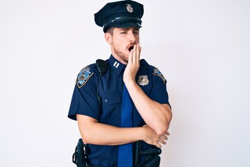 Young caucasian man wearing police uniform bored yawning tired covering mouth with hand. restless and sleepiness.