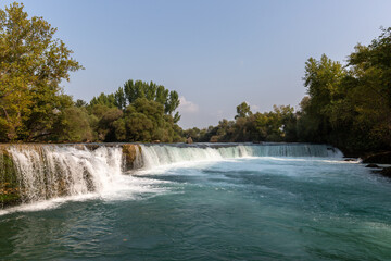 Fototapeta premium Big waterfall in the forest and empty blue sky