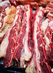 large cuts of raw beef and lamb meat are laid out on the counter in a butcher shop in a large food market