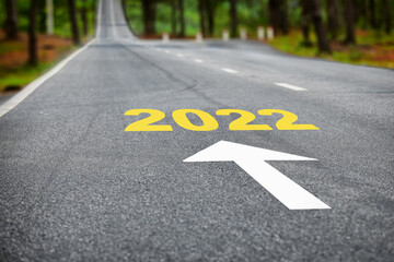 New year 2022 on asphalt road surface with white arrow. Business beginning concept and keep moving forward idea