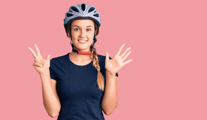 Obraz na płótnie Canvas Beautiful caucasian woman wearing bike helmet showing and pointing up with fingers number eight while smiling confident and happy.