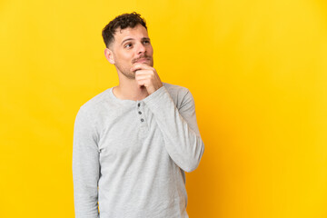 Young caucasian handsome man isolated on yellow background looking up while smiling