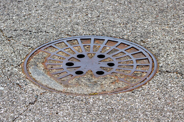 Old manhole cover on asphalt street.