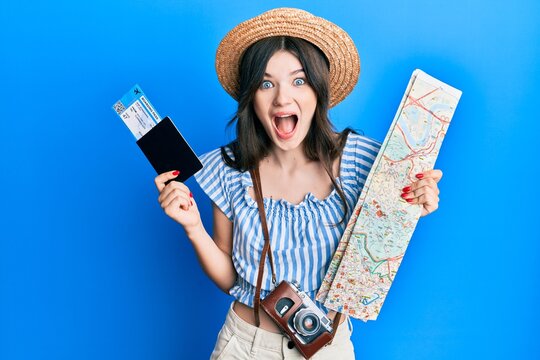 Young beautiful caucasian girl holding passport and city map celebrating crazy and amazed for success with open eyes screaming excited.