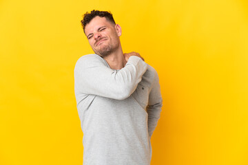 Young caucasian handsome man isolated on yellow background suffering from pain in shoulder for having made an effort