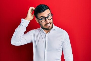 Young hispanic businessman wearing shirt and glasses confuse and wonder about question. uncertain...