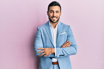 Young hispanic businessman wearing business jacket happy face smiling with crossed arms looking at...