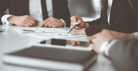 Unknown businessmen and woman sitting, working and discussing questions at meeting in modern office, close-up