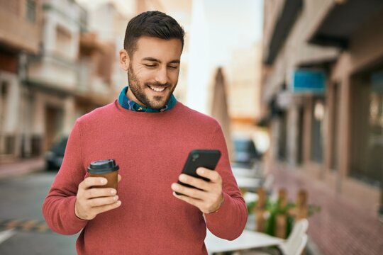 Young hispanic man using smartphone and drinking coffee at the city.