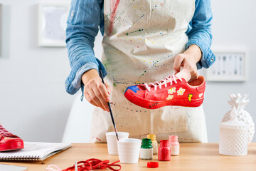 Fashion entrepreneur repainting and repurposing used pair of shoes