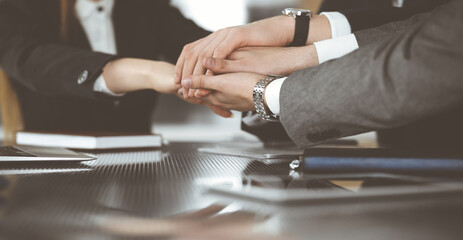 Unknown business people group joining hands in modern office. Businessmen and women making circle with their hands as a team, close-up