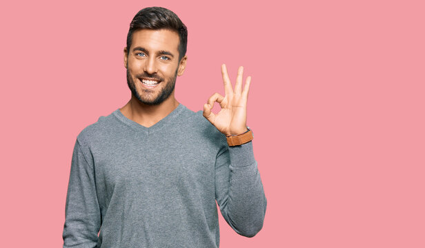 Handsome hispanic man wearing casual clothes smiling positive doing ok sign with hand and fingers. successful expression.