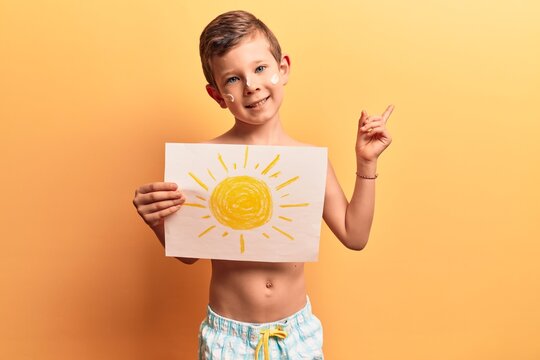 Cute blond kid wearing swimwear and summer hat smiling happy pointing with hand and finger to the side