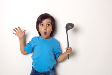 boy in a blue T-shirt stands with a ladle on a white background in the studio