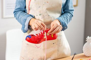 Woman artist doing arts and crafts project and customizing shoes