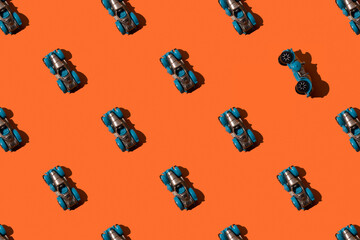 Toy retro car convertible in seamless pattern on orange background. One car turned on its side.