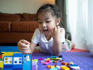 Asian child girl playing block toy to create house