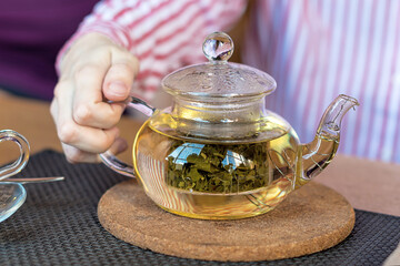 Teapot with herbal tea. The concept of healthy eating. Man's hand holding a teapot.