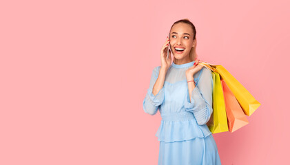 Smiling lady talking on phone holding shopping bags