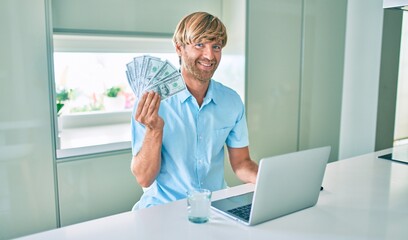 Fototapeta na wymiar Young irish man using laptop holding dollars at home.