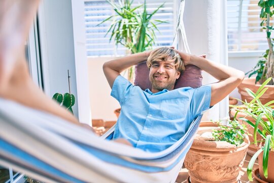 Middle age handsome man at the terrace of his house relaxing lying on a hammock