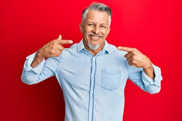 Middle age grey-haired man wearing casual clothes smiling cheerful showing and pointing with fingers teeth and mouth. dental health concept.