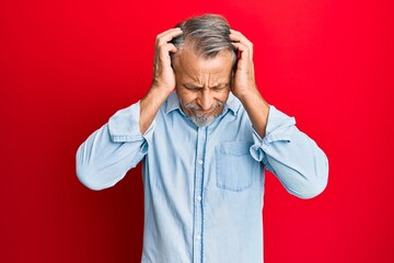 Middle age grey-haired man wearing casual clothes suffering from headache desperate and stressed because pain and migraine. hands on head.