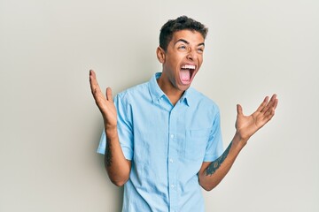 Young handsome african american man wearing casual clothes crazy and mad shouting and yelling with aggressive expression and arms raised. frustration concept.