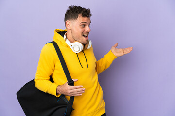 Young sport caucasian man with bag isolated purple background with surprise expression while looking side