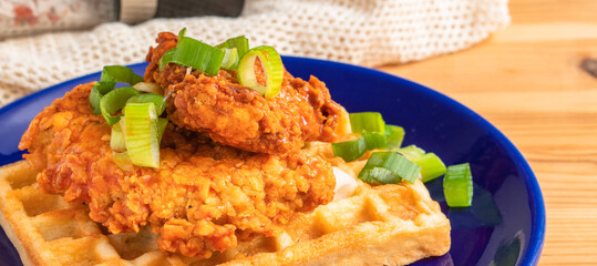 Homemade Southern American comfort street food fresh deep fried crispy stacked chicken wings with buffalo red chili spicy hot sauce and waffle sweet maple syrup