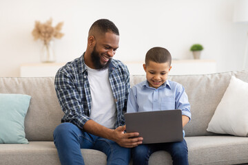 African American Father Teaching Son To Use Laptop At Home