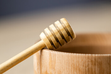 Honey dripping from honey dipper in wooden bowl. Close-up. Healthy organic. Thick honey dipping...