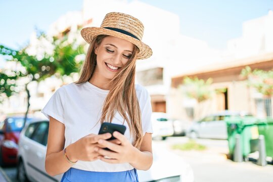 Young blonde woman on vacation smiling happy using smartphone at street of city