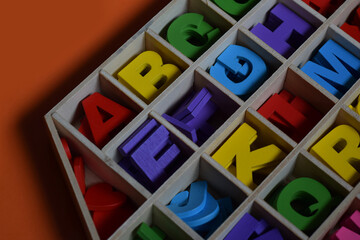 Colourfull Wooden Alphabet in Wooden Box With Orange  Background