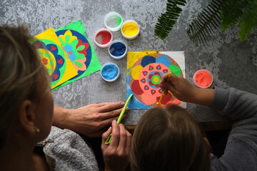 a mandala made of colored sand, the mom with the girls