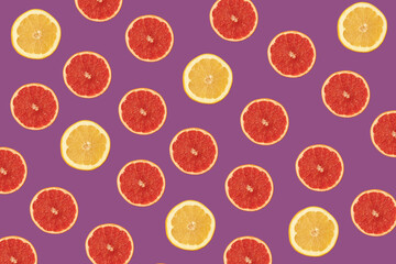 Pattern made of red and yellow grapefruit on vivid purple background. Fresh organic food in vibrant colors.
