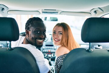 Young interracial couple smiling happy at the car.