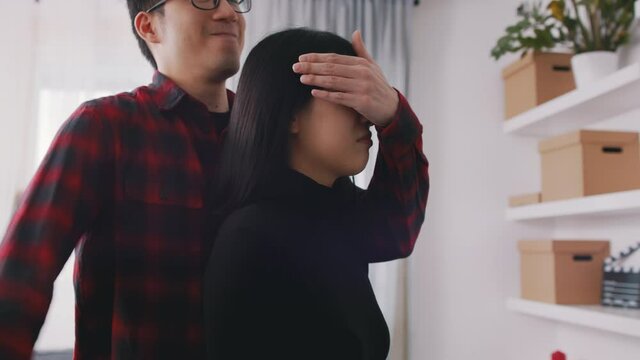 Young man closing eyes of his girlfriend and giving her bouquet of red roses. Haopy Valentines day. High quality 4k footage