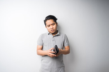 Young Asian man, stressful face expression when looking in empty wallet, economy problem, bankruptcy or broke concept, isolated portrait, selective focus