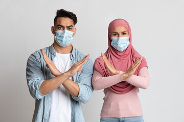 Anti-Vaccination Movement. Confident Muslim Couple In Medical Masks Crossing Hands Near Chest