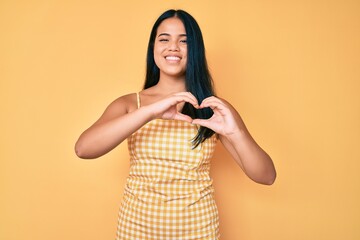 Young beautiful asian girl wearing casual clothes smiling in love showing heart symbol and shape with hands. romantic concept.