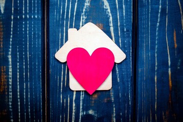 The symbol of the house with heart on wooden background
