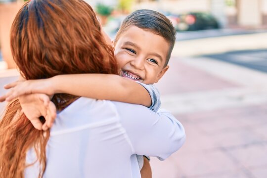 Adorable latin mother and son smiling happy hugging at the city.