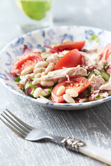  Salad with tuna, tomatoes and cucumber. Wooden background. Close up.