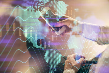 Double exposure of man's hands holding and using a digital device and forex graph drawing. Financial market concept.