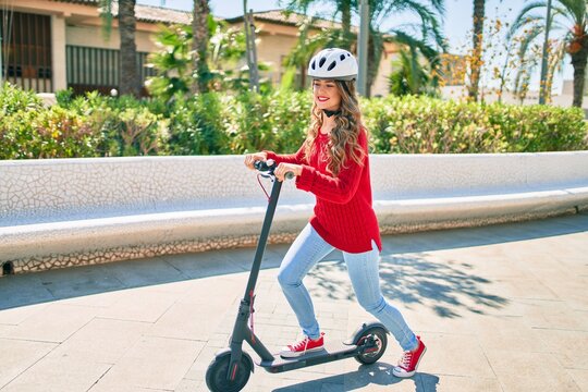Young blonde girl smiling happy using electric scooter at the park.
