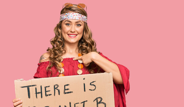Young blonde girl wearing hippie style holding there is no planet b banner pointing finger to one self smiling happy and proud