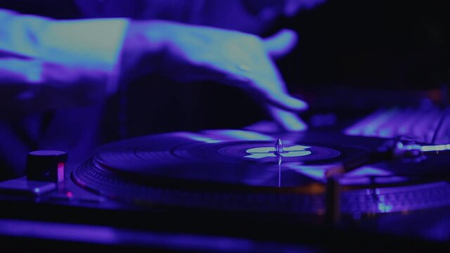 The DJ puts the record in the turntable and plays club music. Retro analog audio equipment for retro DJs at a beach party festival with a crowd of people. Summer nightlife of the disco club outside
